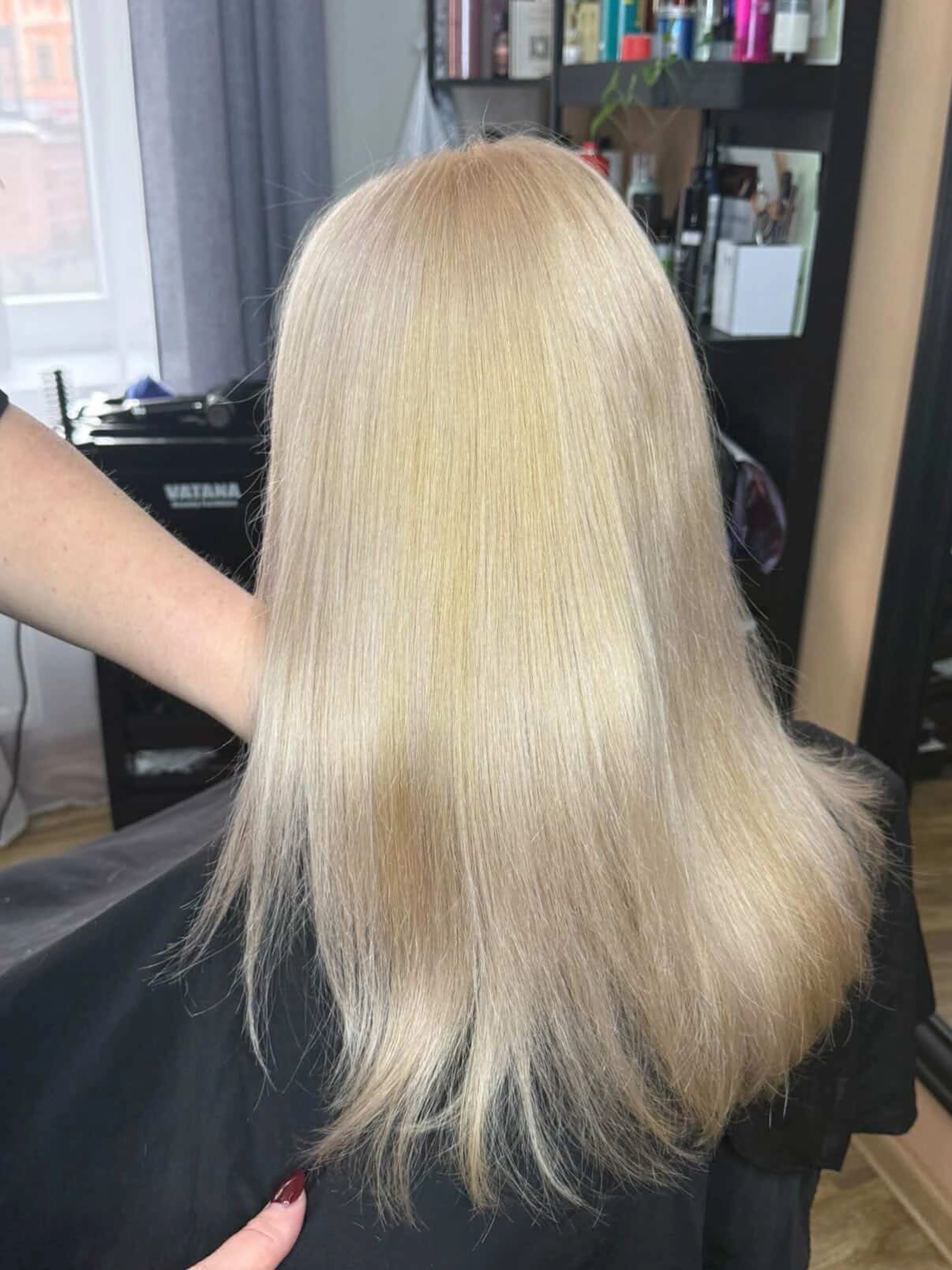 Hladké rovné blond vlasy zobrazené zezadu.