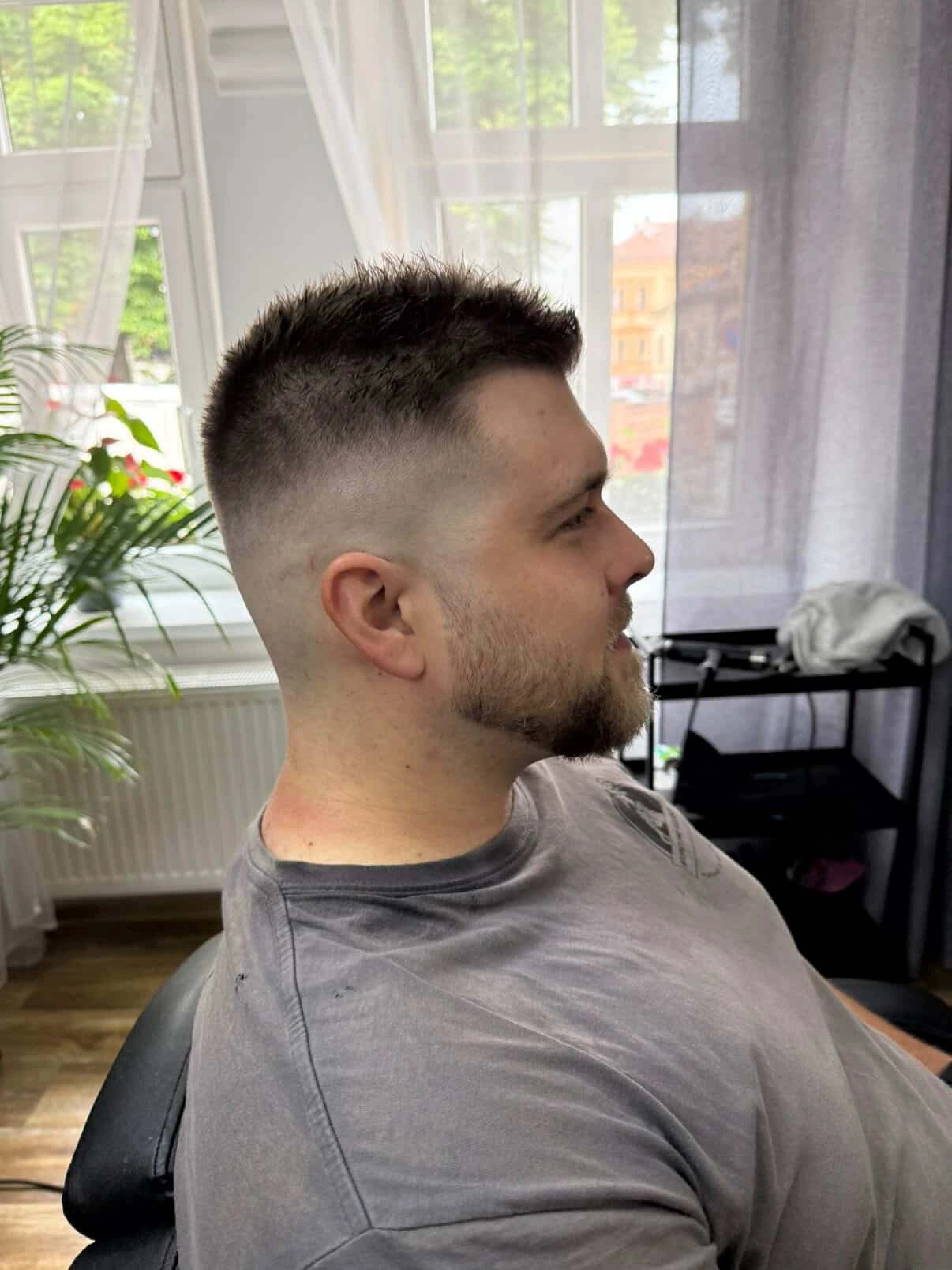 Pánský krátký střih s vysokým fade přechodem a upravenými vousy.