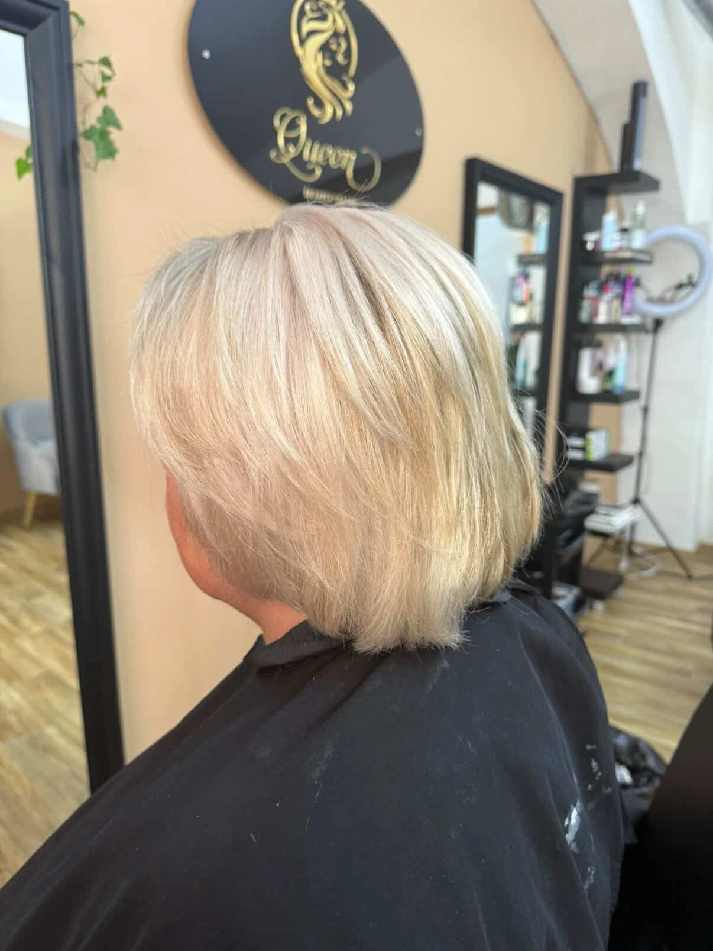 Kratší vrstvený blond účes zobrazený z profilu.